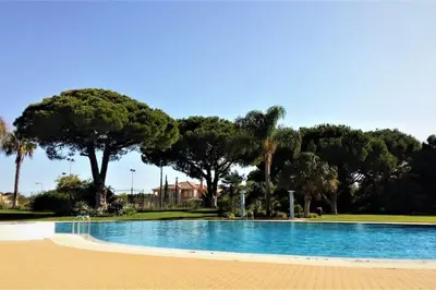 an empty swimming pool with trees in the background at Charming 3 bed apartment @ Al-Sakia Village in Quarteira