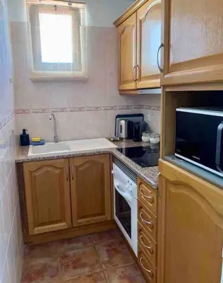 a kitchen with wooden cabinets and a sink and a microwave at Charming 5 bed Private Villa - Quarteira in Quarteira