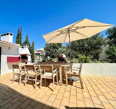 a table and chairs with an umbrella on a patio at Charming 5 bed Private Villa - Quarteira in Quarteira