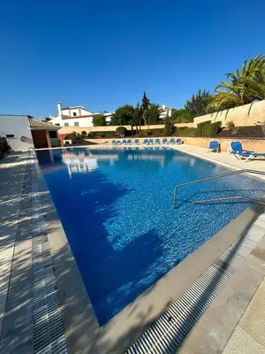 a large swimming pool with blue water and chairs at Three Bedroom Sea View Townhouse Villa in Albufeira