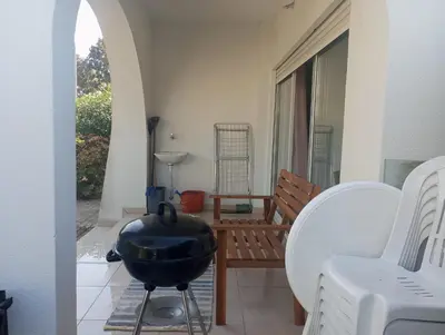 a patio with a bbq grill and a chair at Espaçoso apartamento com excelente espaço exterior in Albufeira