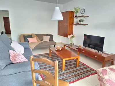 a living room with a couch and a table at Espaçoso apartamento com excelente espaço exterior in Albufeira