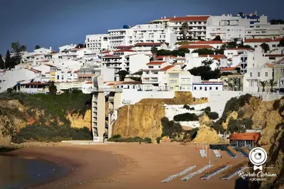 a group of white buildings on a hill with a beach at Espaçoso apartamento com excelente espaço exterior in Albufeira