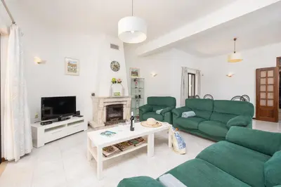 a living room with green couches and a fireplace at Villa Cavaco in Vilamoura