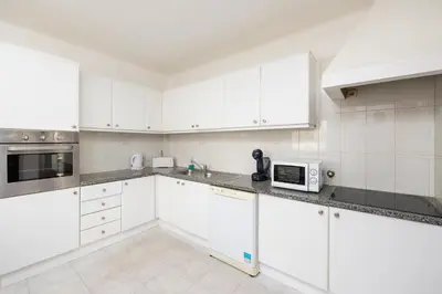 a white kitchen with white cabinets and a microwave at Villa Cavaco in Vilamoura