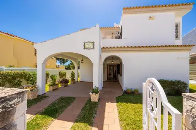 a white house with an archway and a fence at Villa Cavaco in Vilamoura