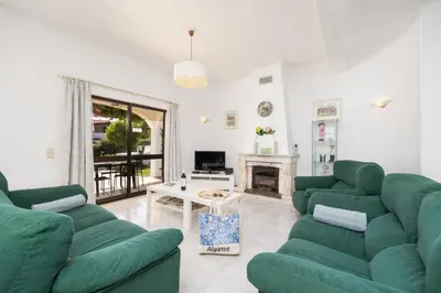 a living room with two green couches and a fireplace at Villa Cavaco in Vilamoura