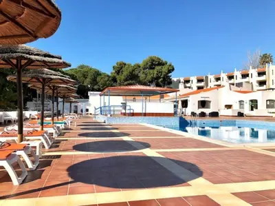 a resort with a pool and chairs and umbrellas at Lagoon Bleue in Albufeira