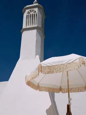 a white lighthouse with a parasol in front of it at Solar do Bisavô in Bordeira