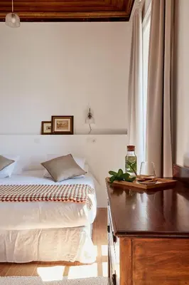a bedroom with a bed and a table with a glass of wine at Solar do Bisavô in Bordeira