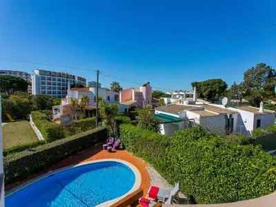 a swimming pool with chairs and an umbrella next to a building at Charming Vilamoura Villa Short Walk To Marina Villa O Clube 3 Bedrooms in Quarteira