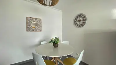 a white dining room with a white table and chairs at Quarteira Frente Praia II by HomeSlow Rentals in Quarteira