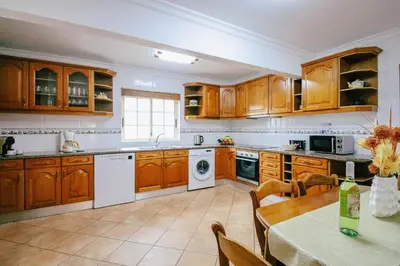 a large kitchen with wooden cabinets and a table with a tableablish at Villa Punta Cana by Algarve Vacation in Albufeira
