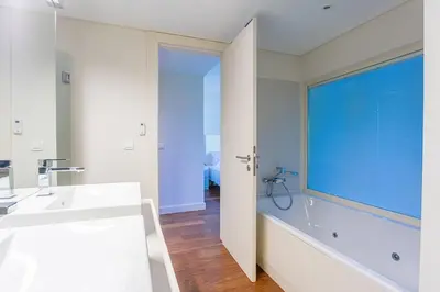 a bathroom with a tub and a sink and a window at Villa Adelaide in Quarteira