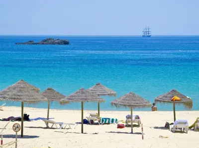 a beach with chairs and umbrellas and the ocean at Villa Adelaide in Quarteira
