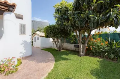 a garden with trees and a sidewalk next to a house at VILLA ROSADO - Moradia para 6 com AC, jardim a 5 min do centro de Albufeira in Albufeira