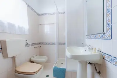 a white bathroom with a toilet and a sink at VILLA ROSADO - Moradia para 6 com AC, jardim a 5 min do centro de Albufeira in Albufeira