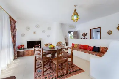 a dining room and living room with a table and chairs at VILLA ROSADO - Moradia para 6 com AC, jardim a 5 min do centro de Albufeira in Albufeira