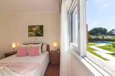 a bedroom with a bed with pink pillows and a large window at Vilamoura M.M. Holidays T2 in Vilamoura
