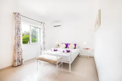 a white room with a bed and a table and a window at Villa Isla Bella by Algarve Vacation in Albufeira