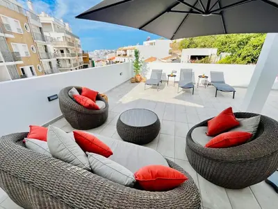 a patio with wicker chairs and tables and an umbrella at Boutique Style Town House in Albufeira