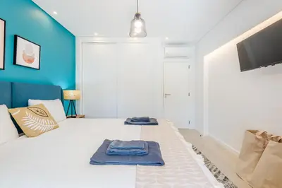 a bedroom with a white bed with blue walls at Balaia apartment at Albufeira in Albufeira