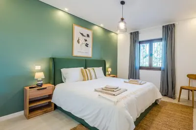 a bedroom with a large bed with a green wall at Balaia apartment at Albufeira in Albufeira