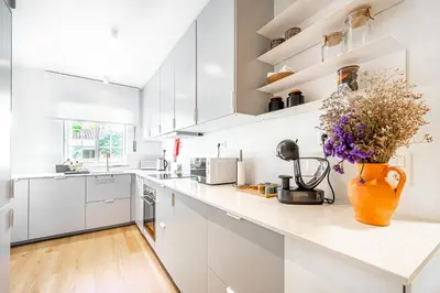 a kitchen with white cabinets and a vase of flowers on the counter at BeGuest Falesia Beach & Garden in Albufeira