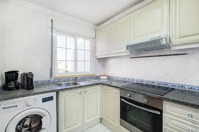 a kitchen with white cabinets and a washer and dryer at Apart Ocean View in Albufeira