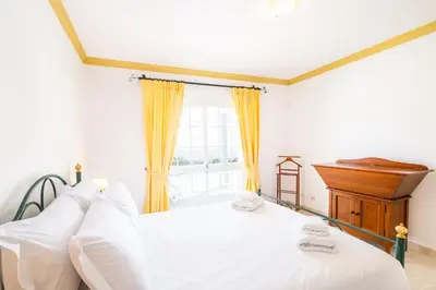 a bedroom with a white bed and a piano at Villa Ventura Heritage in Albufeira