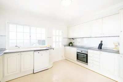 a white kitchen with white cabinets and appliances at Villa Ventura Heritage in Albufeira