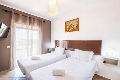 two beds in a room with a window at Milene Guest House in Albufeira