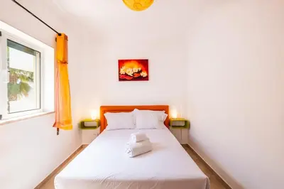 a bedroom with a white bed with a window at Milene Guest House in Albufeira