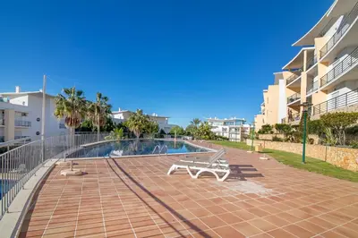 a swimming pool with a bench next to a building at Apartamento da Ourada Marina luz in Albufeira