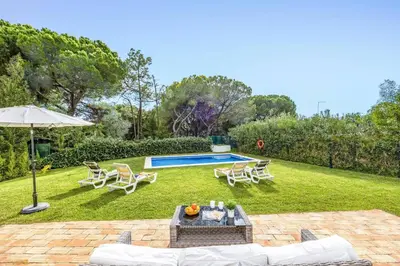 a backyard with a pool and chairs and an umbrella at Villa Balaia by Villa Plus in Olhos de Água