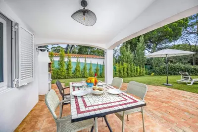 a patio with a table with chairs and an umbrella at Villa Balaia by Villa Plus in Olhos de Água
