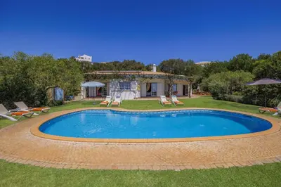 a pool in a yard with chairs and a house at Villa Casa do Barrocal by Villa Plus in Loulé