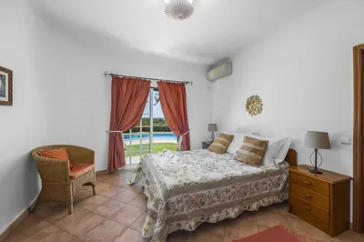 a bedroom with a bed and a chair and a window at Villa Casa do Barrocal by Villa Plus in Loulé