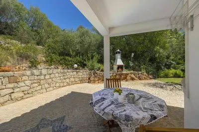 a table and chairs on a patio with a stone wall at Villa Casa do Barrocal by Villa Plus in Loulé