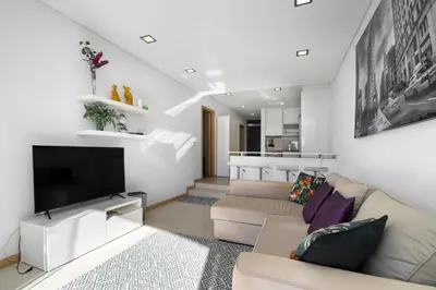 a living room with a couch and a television at Amazing Flat In Olhos de Água in Olhos de Água