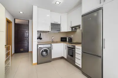 a kitchen with white cabinets and a stainless steel refrigerator at Amazing Flat In Olhos de Água in Olhos de Água