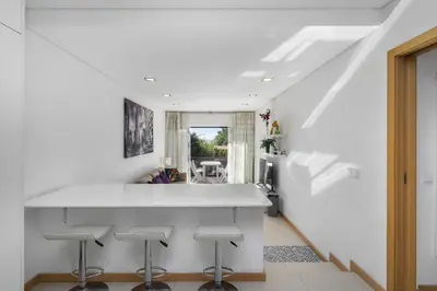 a kitchen with a white counter and stools at Amazing Flat In Olhos de Água in Olhos de Água