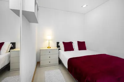 a white bedroom with a bed with red pillows at Amazing Flat In Olhos de Água in Olhos de Água