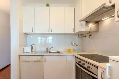 a kitchen with white cabinets and a sink at Apartamento LIMA by Sunnyway in Albufeira