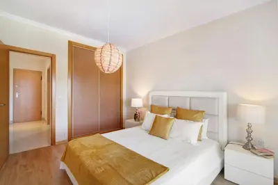 a white bedroom with a large bed and a chandelier at Apartamento Loft 39 by Sunnyway in Albufeira