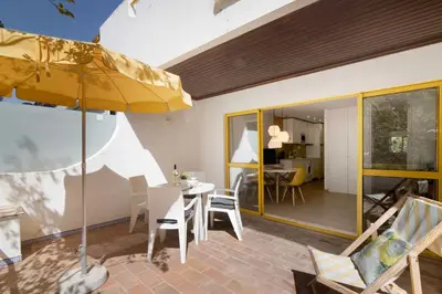 a patio with a table and chairs and a yellow umbrella at África Minha in Vilamoura