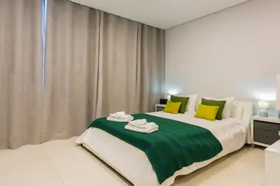 a bedroom with a large bed with green and yellow pillows at MARC - Vilamoura in Vilamoura