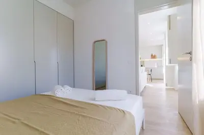 a white bedroom with a bed and a mirror at Modern & Bright Faro Mercado Apt 12 by Lisbeyond in Faro