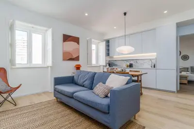 a living room with a blue couch and a kitchen at Modern & Cozy Faro Mercado Apt 11 by Lisbeyond in Faro