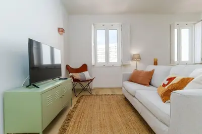 a living room with a white couch and a tv at Modern & Cozy Faro Mercado Apt 21 by Lisbeyond in Faro